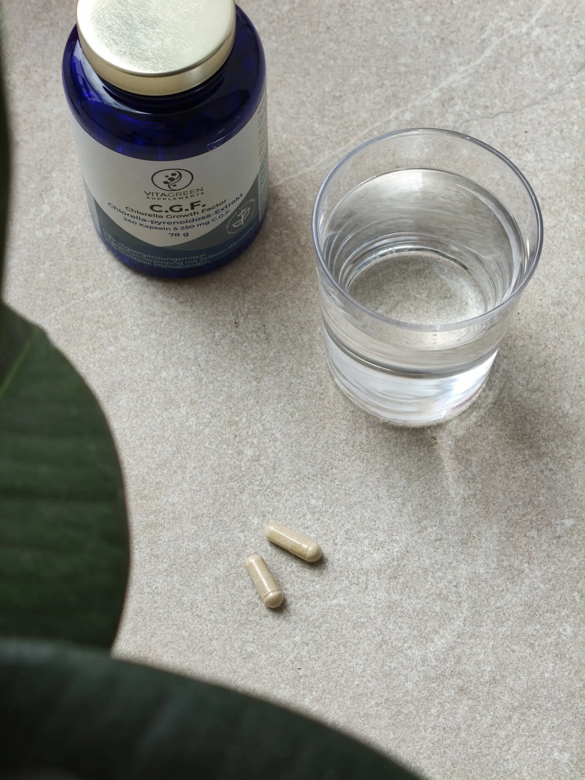 C.G.F. Dose, zwei Kapseln und ein Glas Wasser