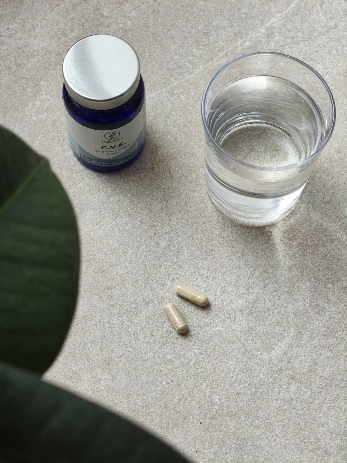 C.V.E. Dose, zwei Kapseln und ein Glas Wasser