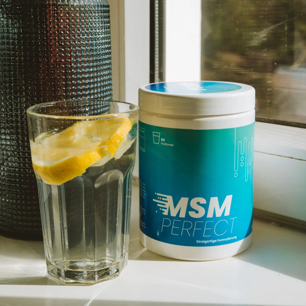 MSMperfect Dose neben einem Glas Wasser mit Zitrone am Fenster