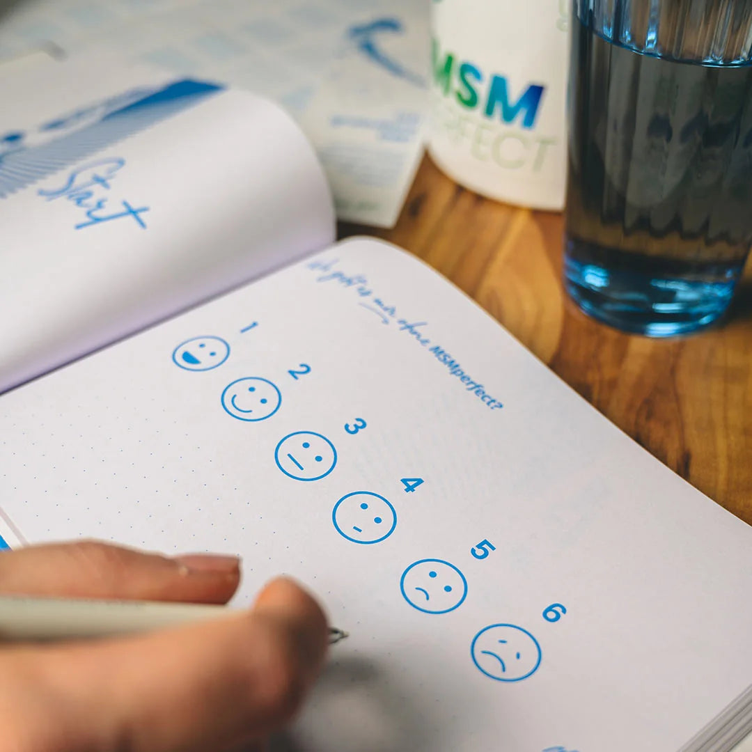 Notizbuch mit Stimmungsskala neben MSMperfect Dose und einem Glas Wasser