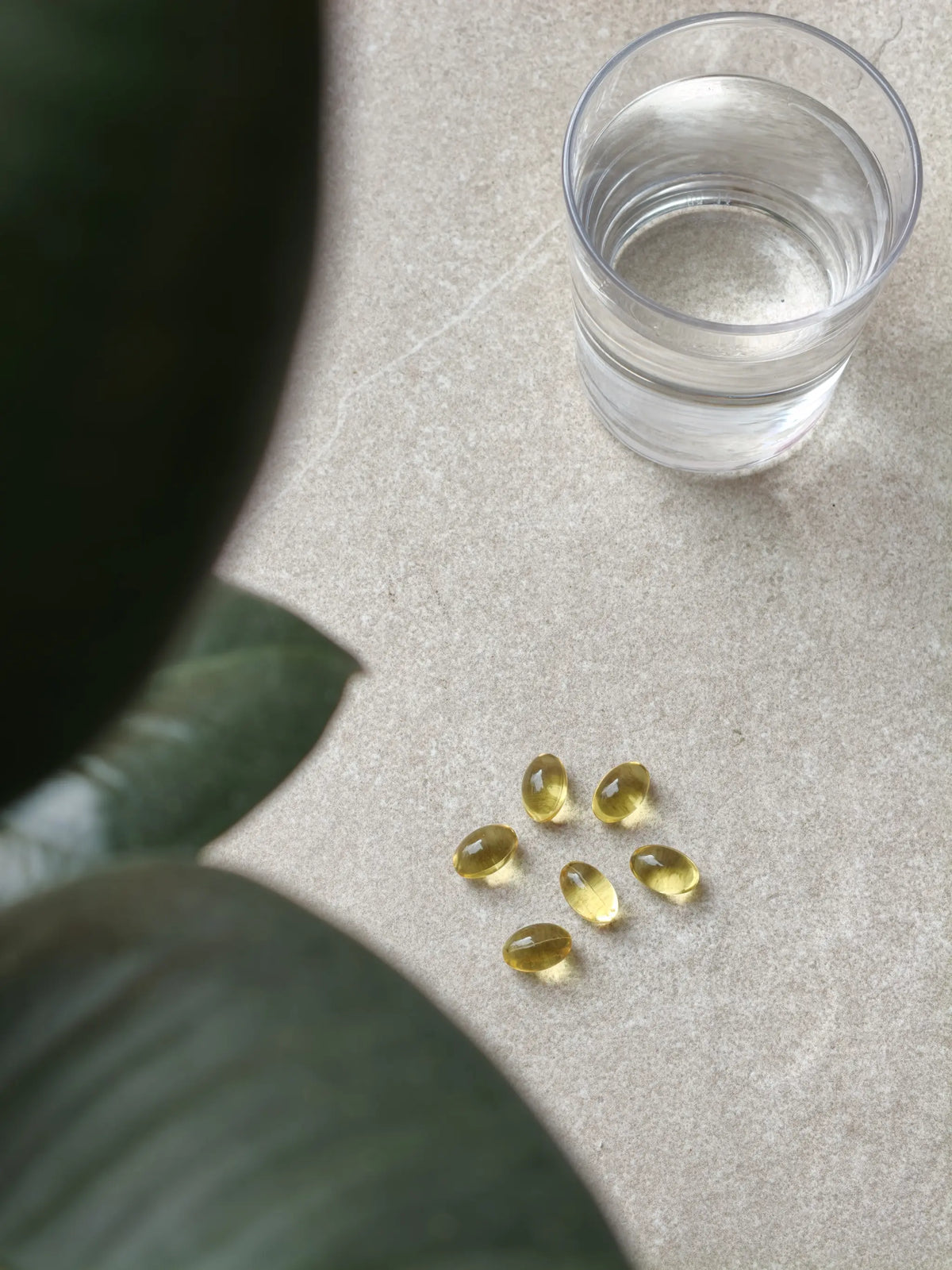 Omega-3 Fischöl Kapseln neben einem Glas Wasser