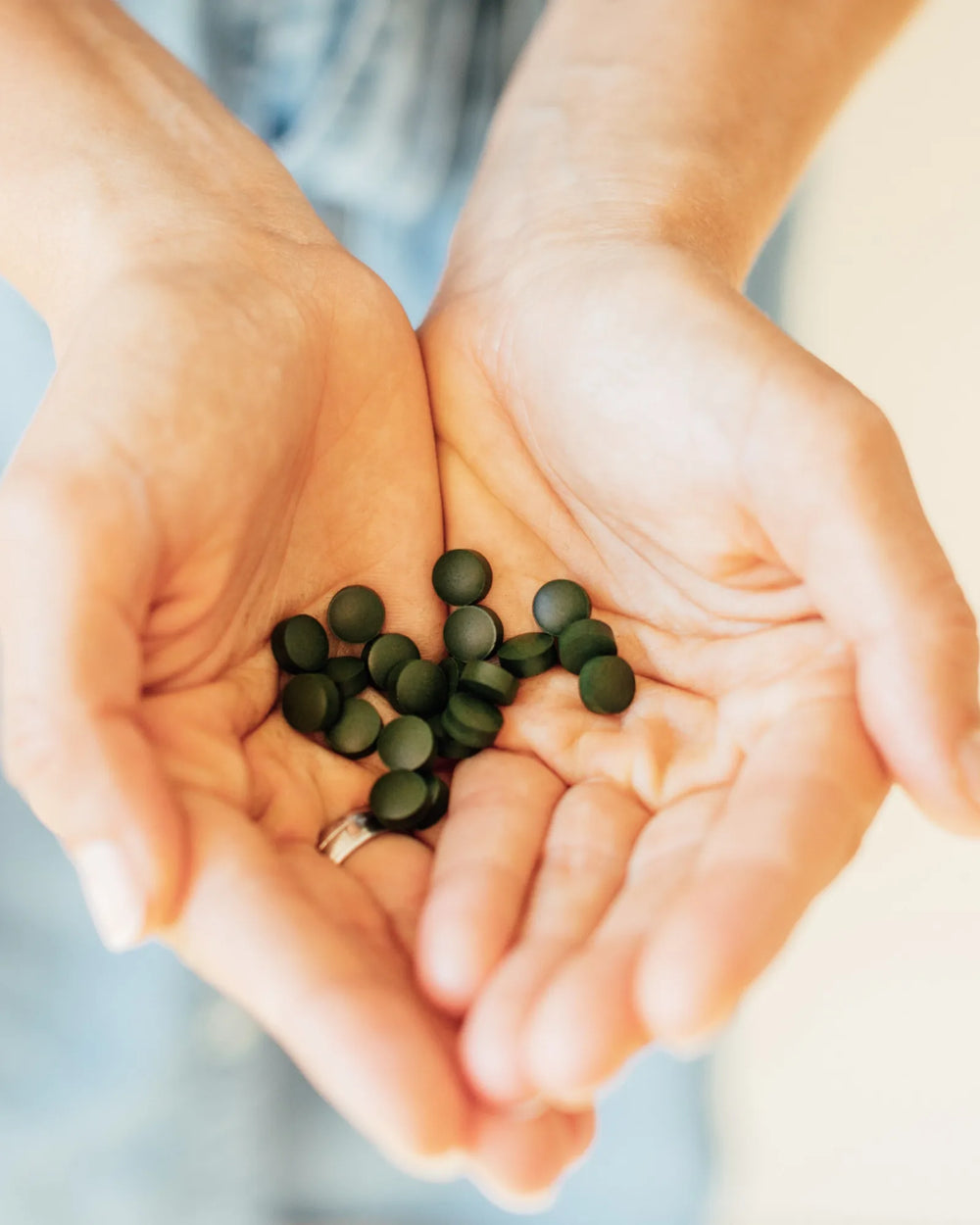 Zwei offene Hände mit einer Handvoll grüner Chlorella-Presslinge, je 200 mg